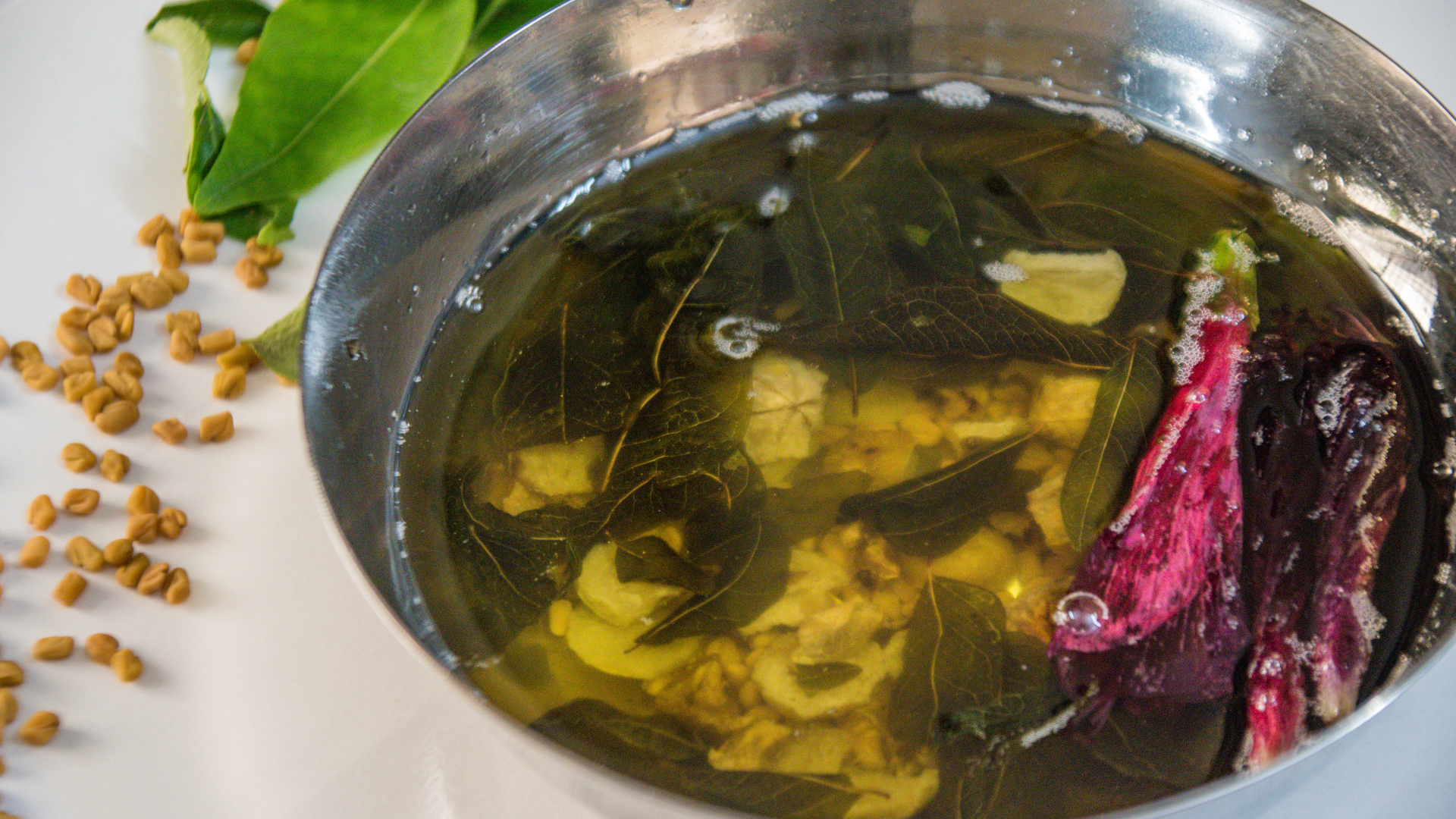 a pan full of oil and herbs. Herbal oil is being prepared.